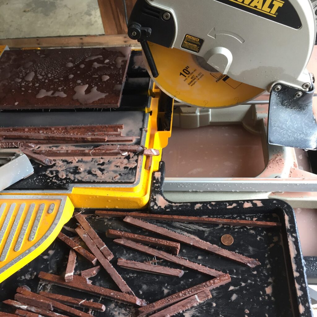 Marble tile on the tray of a wet saw with cut stone strips in the foreground, the earliest photograph in the project