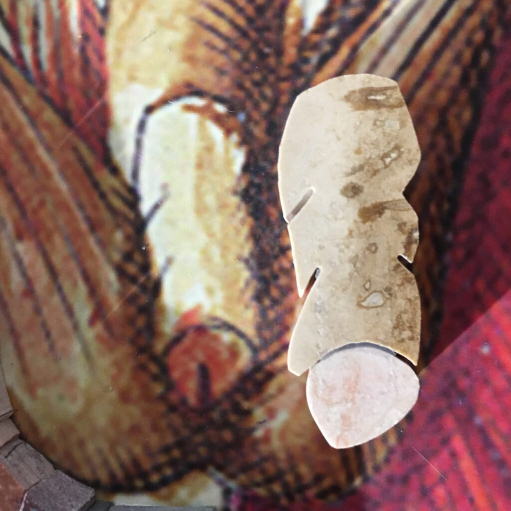 A single piece of mottled travertine lying on the cartoon, next to the printed passage it was cut to match
