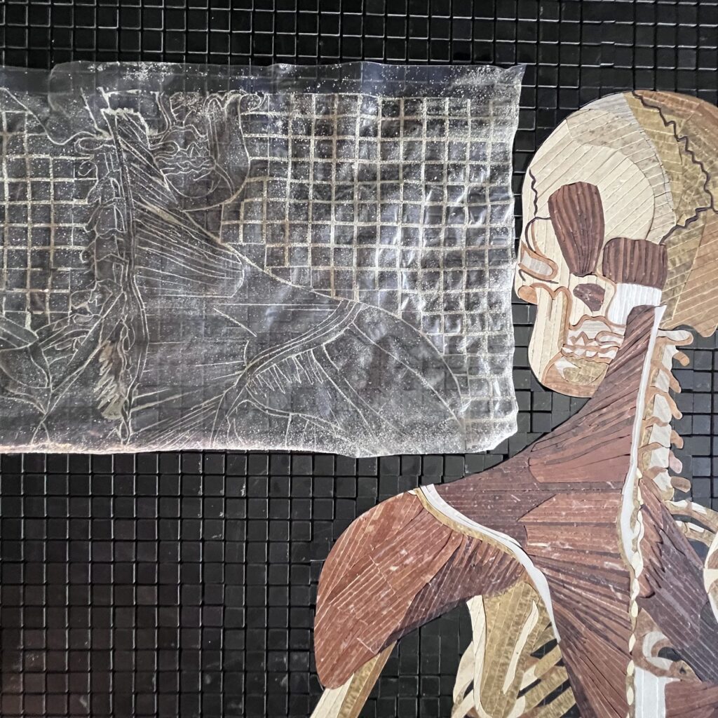 A sheet of peeled tape carrying a sand impression of the entire mosaic, every stone visible in negative, beside the panel it came off